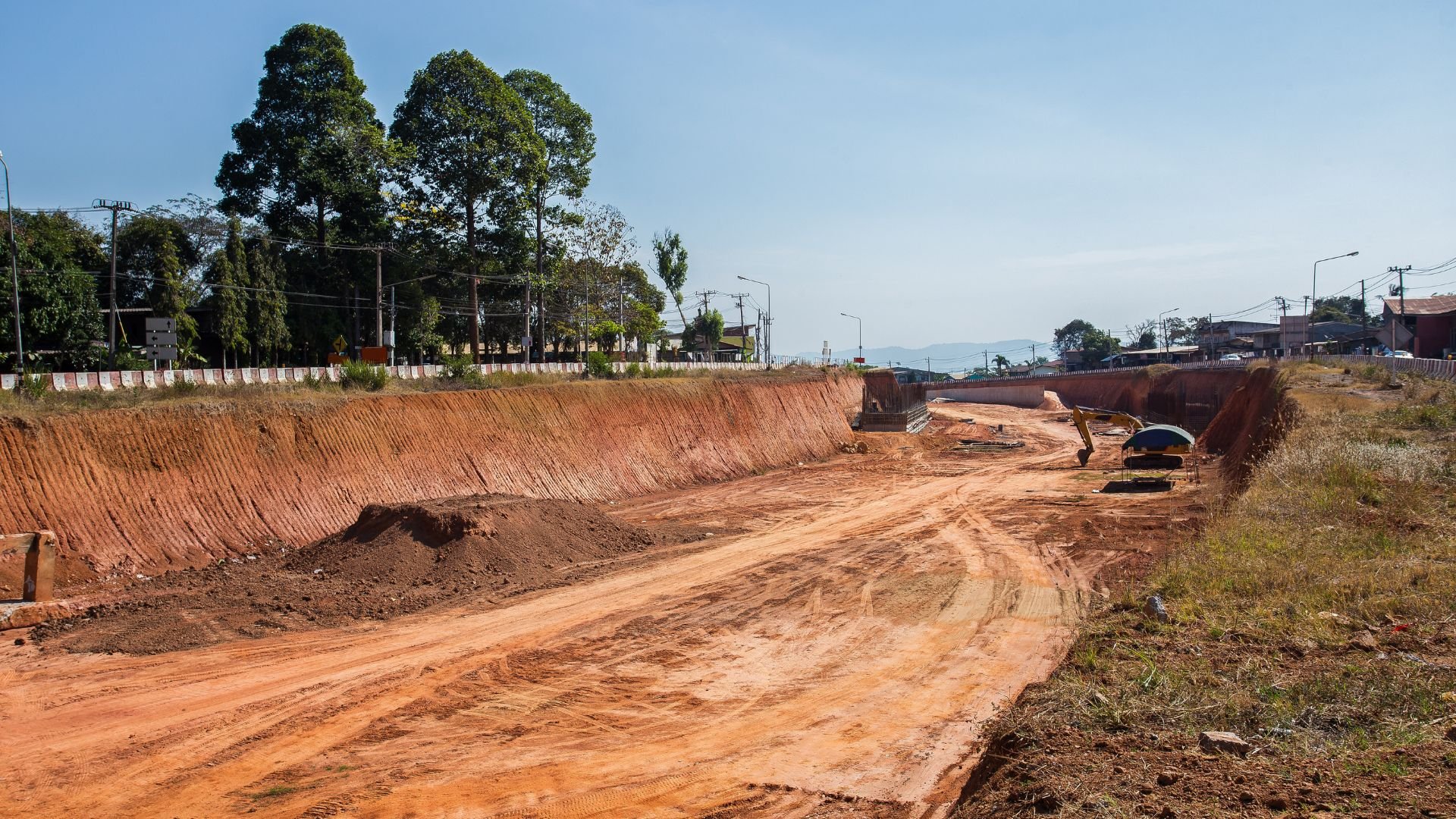 Road construction site with excavated red earth and heavy machinery