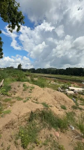 Sandy construction site with mounds of dirt under cloudy summer sky