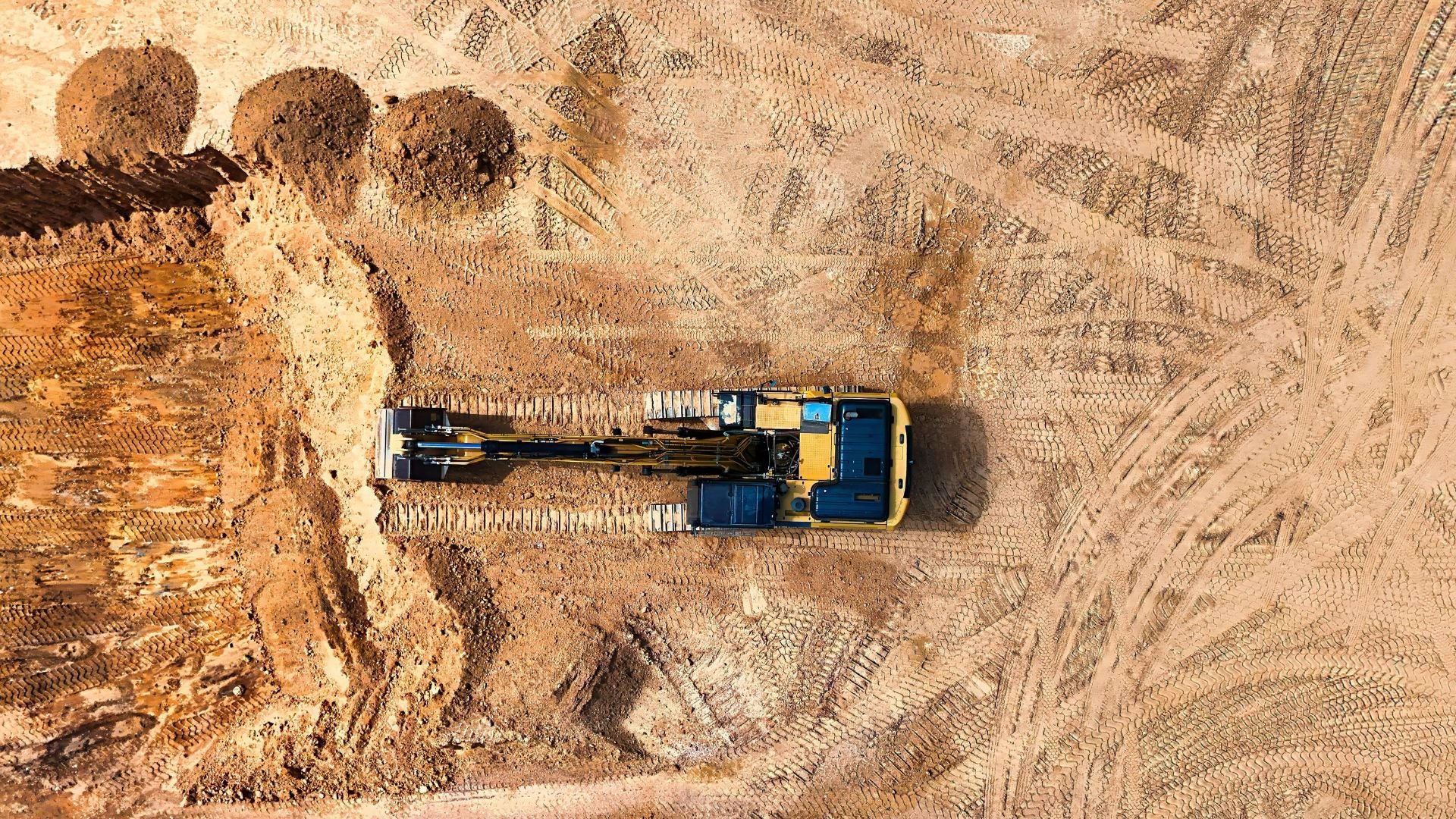 Excavator working on dusty construction site from aerial view